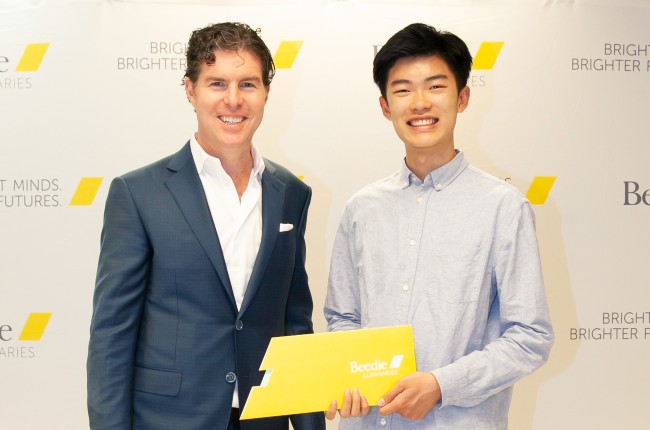 Ryan Beedie (left), standing next to Jason Pang (right), holding a yellow certificate.