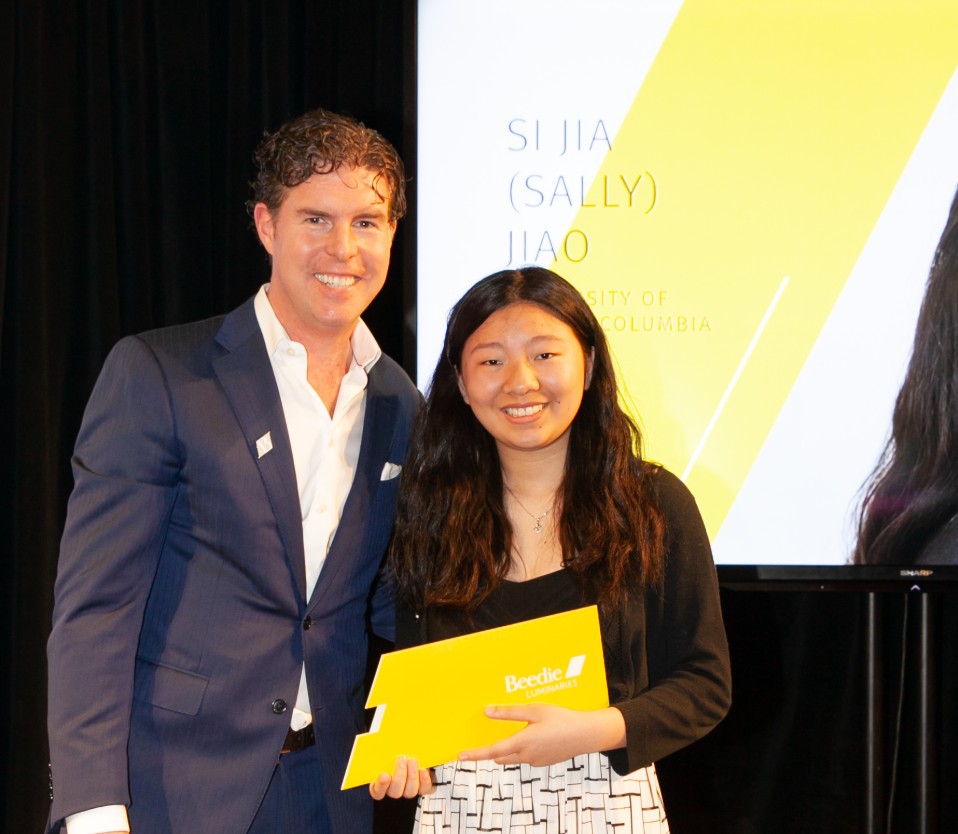Ryan Beedie (left), standing next to Sally Jiao (right), holding a yellow certificate.