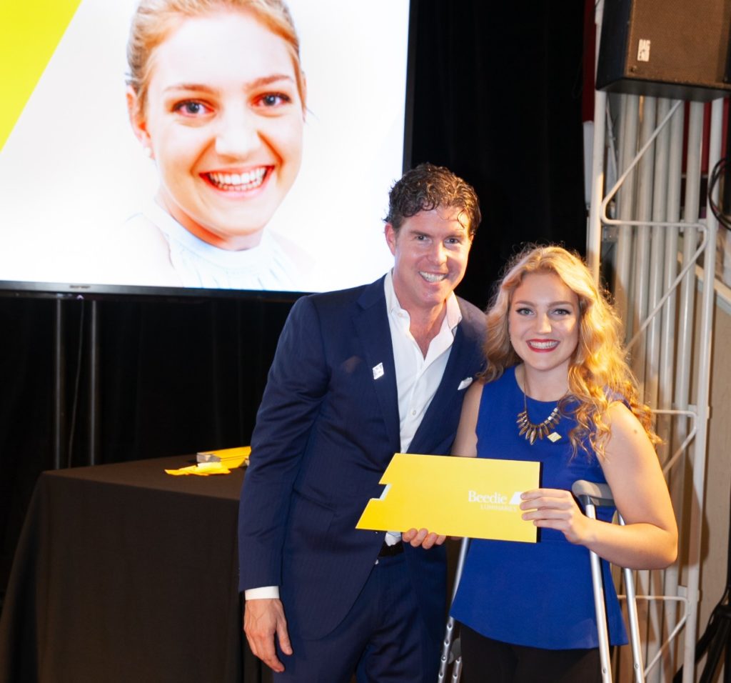 Ryan Beedie (left), standing next to Emily Meier (right), holding a yellow certificate.