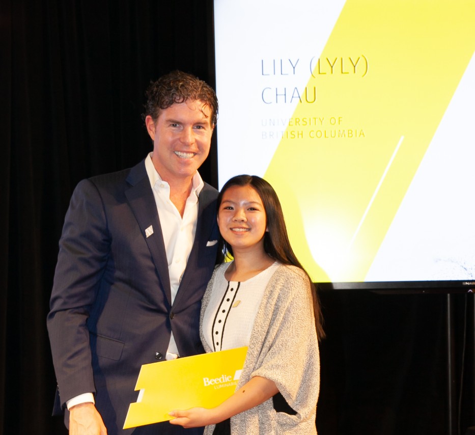 Ryan Beedie (left), standing next to Lily Chau (right), holding a yellow certificate.