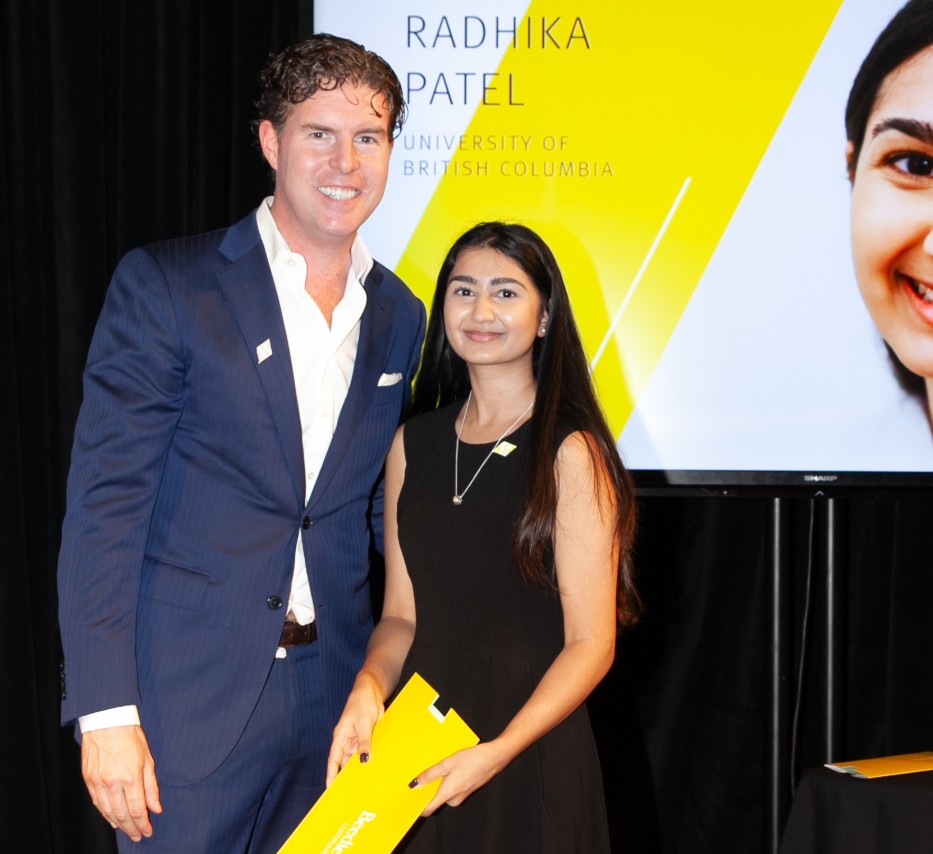 Ryan Beedie (left), standing next to Radhika Patel (right), holding a yellow certificate.