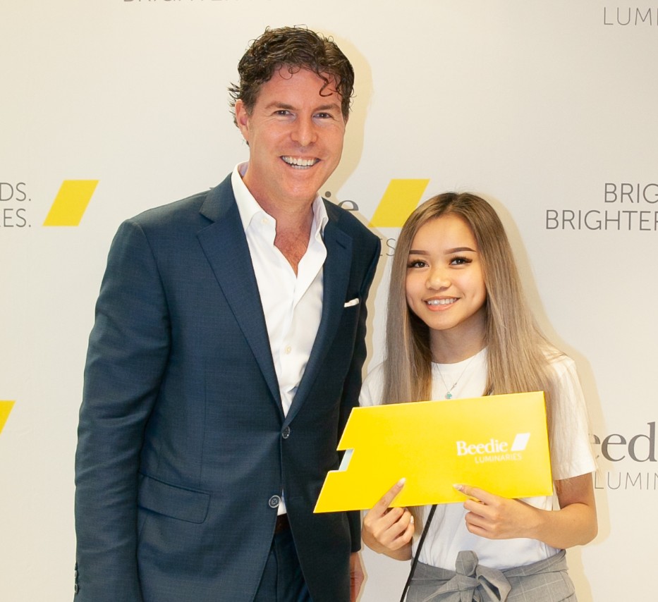 Ryan Beedie (left), standing next to Michelle Ha (right), holding a yellow certificate.