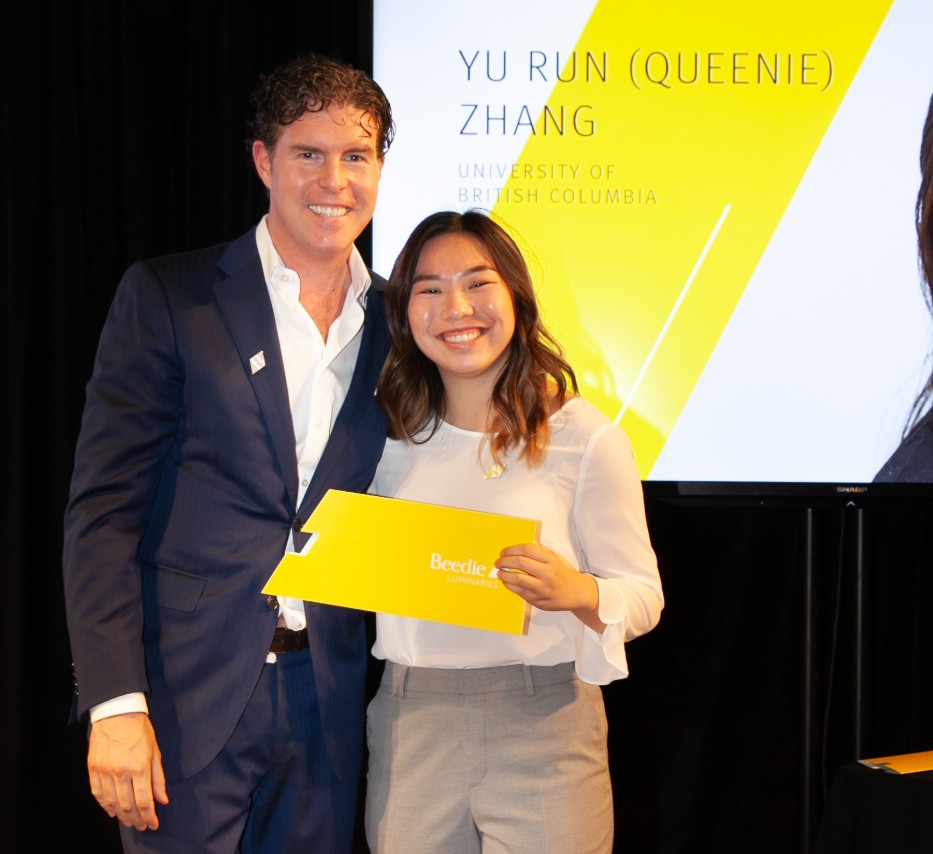 Ryan Beedie (left), standing next to Queenie Zhang (right), holding a yellow certificate.