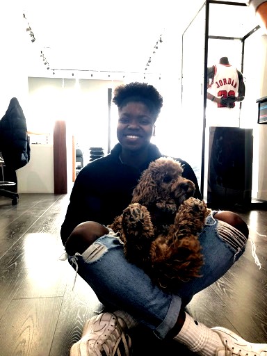 Woman sits cross legged with a dog in her lap.