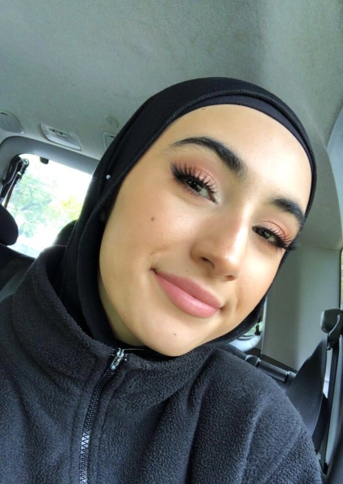Woman in black hijab takes selfie inside of a car.
