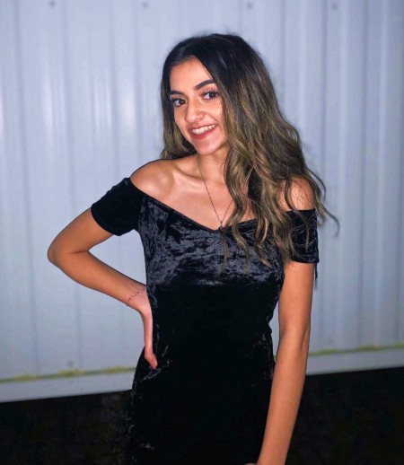 Young woman smiling, wearing a dress for a gala event.